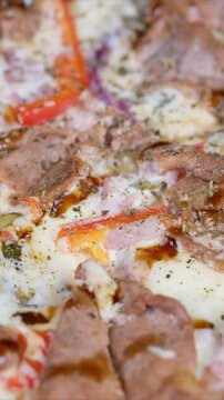 Mouthwatering closeup of delicious glazed meat topped pizza with crispy crust. Visually appealing image showcasing delectable pizza with rich toppings and perfectly crispy base