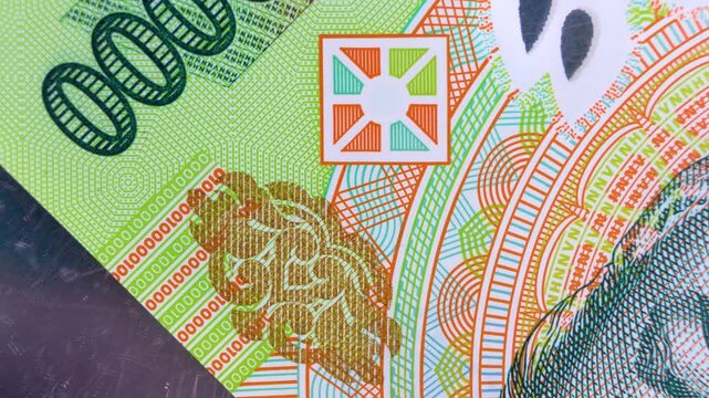 Macro close-up of a 100,000 Vietnamese Dong (VND) polymer note. Features smooth panning over green security patterns, color-shifting ink, and micro-printed numerals. Perfect for finance and travel.