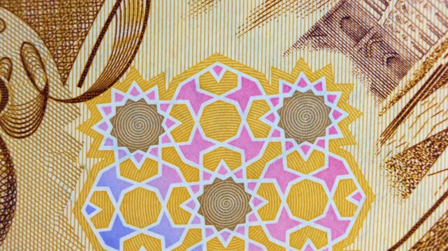 Macro pan of a 1000 Iraqi Dinar bill, showcasing vibrant geometric star patterns and intricate security engravings. High-detail footage of authentic Middle Eastern currency and textured paper.