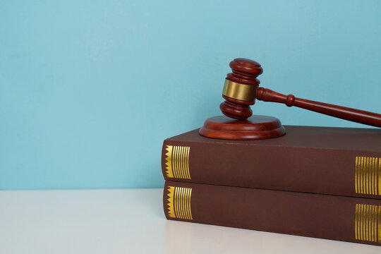 Gavel resting on law books against blue background