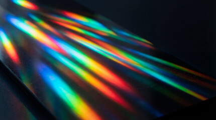 Captivating light spectrum refraction creating vibrant rainbow beams across a dark, textured background. © Jacqueline