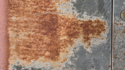 A close-up of a weathered metal surface featuring heavy orange-brown oxidation and peeling grey paint. The texture is gritty and industrial, showcasing the natural decay of steel over time. © Everlasting Dreams