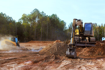Two pieces of heavy equipment are clearing land in dirt prepare area for upcoming projects. © ungvar