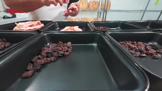 A baker preparing the raisins and ham for pan de jamon in the kitchen