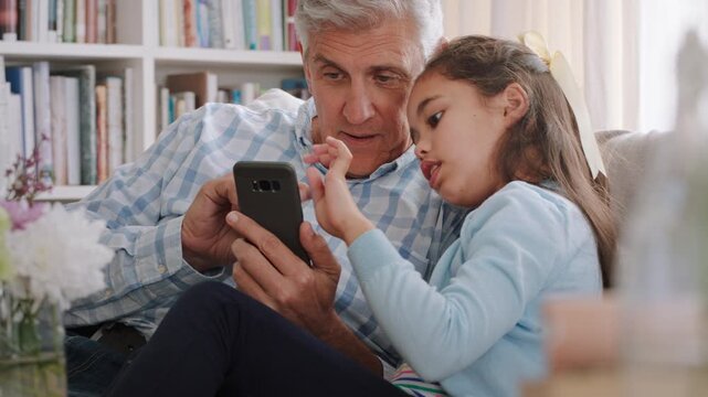Grandpa, phone and talking with girl on sofa in home living room for bonding, learning or visit. App, connection and explain with granddaughter speaking to senior man in apartment for mobile download