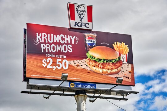Ambato, Ecuador - June 09, 2025: KFC billboard advertising Krunchy Promos featuring a delicious burger, fries, and Pepsi, showcasing vibrant colors and enticing food imagery with copy space