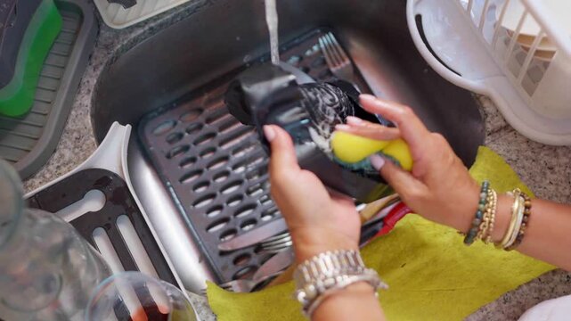 Woman's hands washing dishes in kitchen sink
