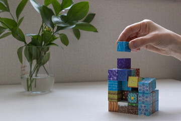 Close-up of a hand stacking colorful magnetic building blocks on a table. Educational magnetic toy for creativity, learning and child development concept © Yulia
