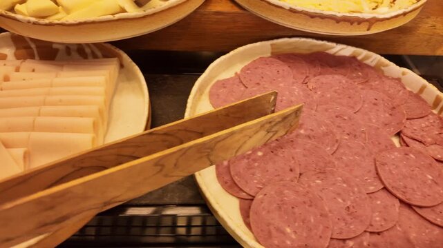 Sliced Salami Platter With Wooden Tongs on Deli Counter 