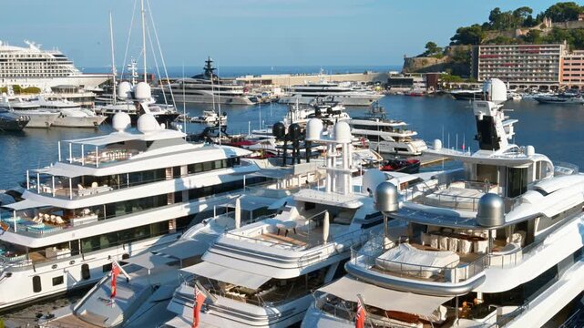 Luxury yachts moored in port Hercules of Monaco at sunny day with scenic view of mediterranean coast