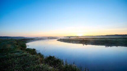 Obraz premium Misty Morning River Landscape At Sunrise With Reflective Water And Clear Sky