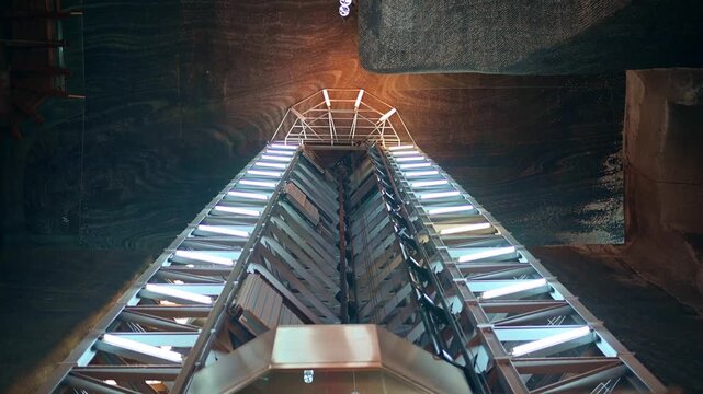 Modern elevator ascending and descending in a deep mine shaft with glowing lights and industrial structure