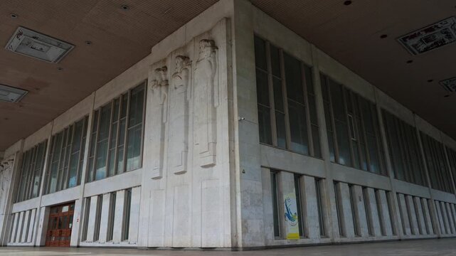 Exterior view of large building corner with tall windows and decorative reliefs