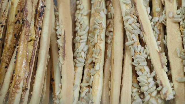 Close up of delicious crispy bread sticks topped with sunflower seeds and sesame