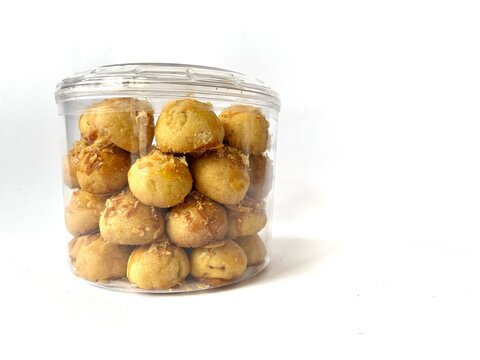A plastic container filled with traditional Indonesian pineapple tart cookies, nastar, isolated on white background.