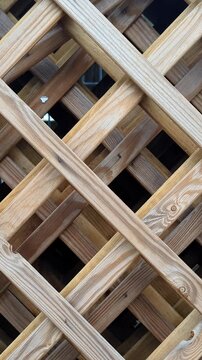 Slow pan shot from left to right across a decorative wooden lattice fence. High-quality 4K footage of a timber trellis pattern, organic garden architecture, and rustic background.