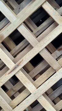 Slow pan shot from left to right across a decorative wooden lattice fence. High-quality 4K footage of a timber trellis pattern, organic garden architecture, and rustic background.