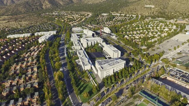 Panning drone shot showing the modern campus of Universidad del Desarrollo with the Andes mountains in the background. Chile, 4K