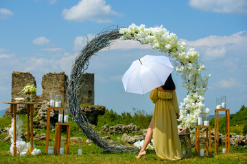 Naklejka premium Elegant bride woman under wedding arch. Romantic wedding arch outdoor scene. Bride under floral wedding decor. Luxury wedding arch with flowers. Beauty bride ceremony concept.