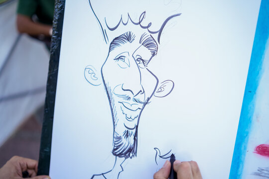 Artist drawing a humorous caricature portrait of a man with a mustache and beard