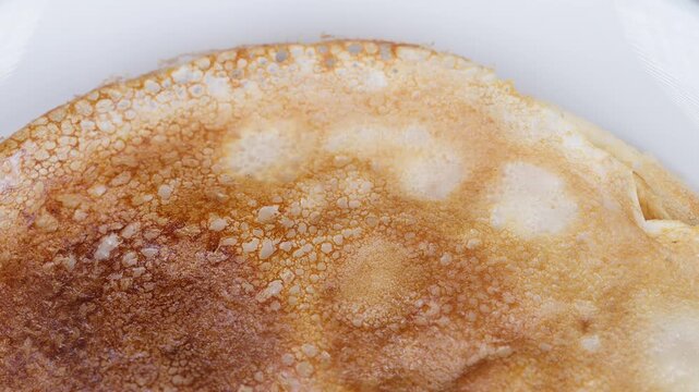 Golden closeup homemade thin pancakes browning on white plate, delicate lacey surface, crisp edges, warm airy texture, light sugar dusting, comforting breakfast mood