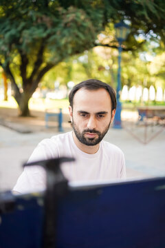 Artist drawing caricatures outdoors in a park with a focused expression