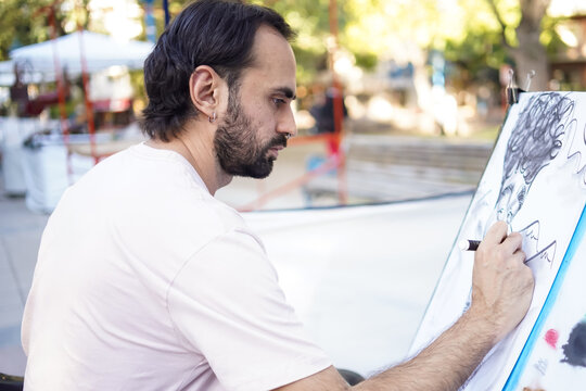 Artist drawing a caricature portrait on a canvas outdoors at a street fair
