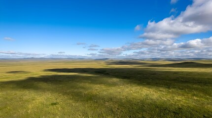 Obraz premium Expansive Green Rolling Hills Landscape Under Dynamic Blue Sky with Moving Cloud Shadows