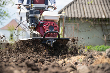 Fototapeta premium Farmer using tiller on a plowed field
