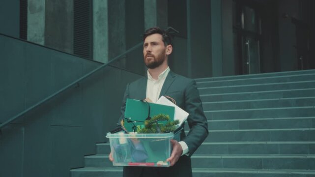 Office worker leaving, Staff member with storage box walking away through empty corporate space with somber attitude