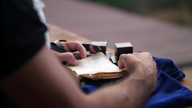 Close up of man praying with tefillin and Hebrew prayer book.