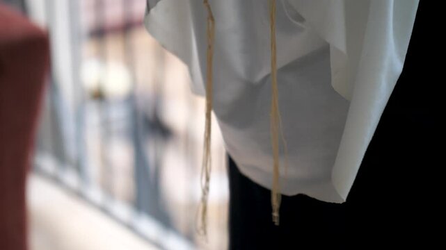 Close-up of tzitzit gently swaying during Jewish prayer ritual.