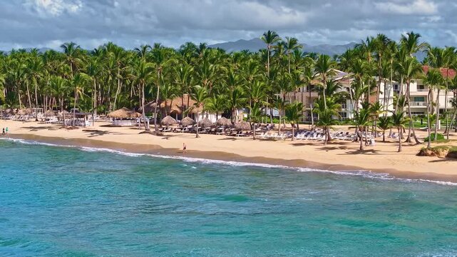 Luxurious tropical resort beach with palm trees on yellow sand. A hotel on the Caribbean coast with turquoise waters and a golden sand beach. A beautiful resort backdrop. Seashore.