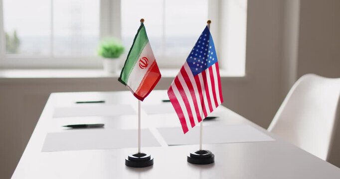 Flags diplomacy negotiations meeting partnership dialogue. Desk flags of Iran and USA on a conference table suggest geopolitics and agreement talks. Concept: international partnership and talks.