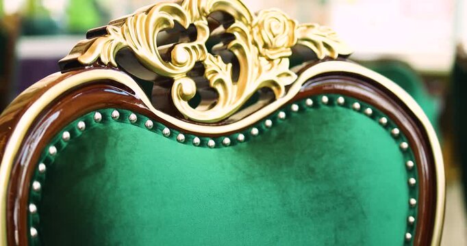 Classic luxury chair with green velvet upholstery and golden carved details, close-up. Elegant vintage interior concept ideal for premium lifestyle and design visuals