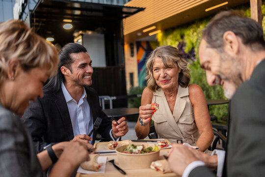 Business colleagues enjoying lunch break at modern outdoor cafe