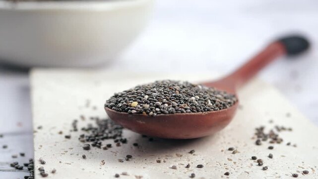 Close-up shot of chia seeds in a wooden spoon on a white surface, showcasing the texture and appearance of healthy superfood