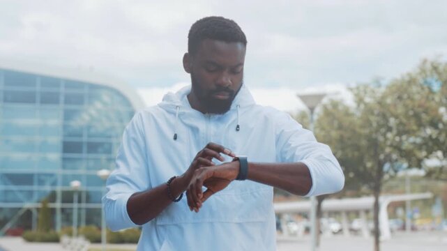 Male individual actively assesses health statistics while surrounded by parks and modern architecture