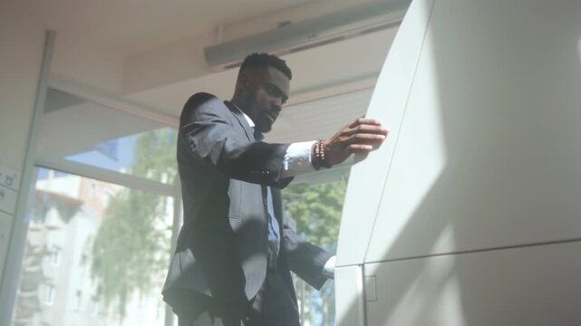Tense executive quickly retrieves receipt outside, Business professional rushes at bank kiosk under sunlight