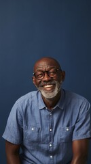 Fototapeta premium Smiling Older Man with Grey Hair, Wearing Glasses and a Denim Shirt