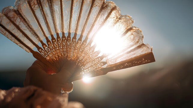 Elegant lace hand fan ornate folding fan sunlight backlit warm glow vintage accessory female hand outdoor