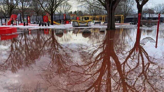 Sudden spring snowmelt floods a public playground, leaving the play area unusable as winter breaks apart and fast meltwater takes over the park.