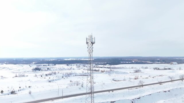 Telecommunication Tower During Winter In A Snow Covered Landscape, Orbiting Aerial Shot.