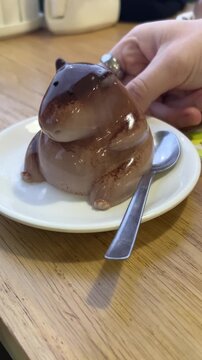 Cute capybara shaped chocolate mousse dessert - kawaii animal pudding being touched