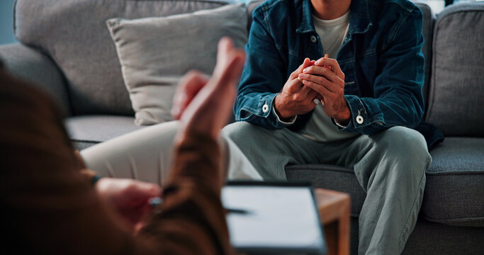 Hands, anxiety and man on sofa by therapist for emotional support, help or advice on mental health. Nervous, notes and person with life coach for therapy, wellness or counseling session at clinic.