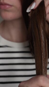 Close up of female hands applying aloe vera gel to brown hair ends. Focus on moisturizing dry tips, improving texture and nourishing damaged strands. Concept of natural hair care and repair. 