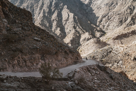 Cyclist on hairpin turn on precipitous mountain road in Oman