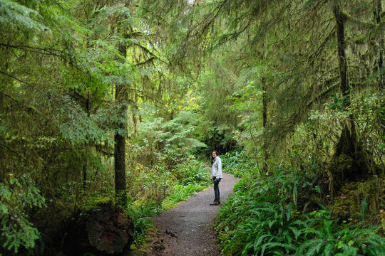 Woman smiles on hiking trail in lush green forest