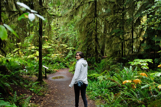 Woman smiling as she hikes through the lush green Quinault Rain Forest