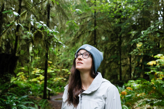 Woman in beanie looking up in lush green national forest